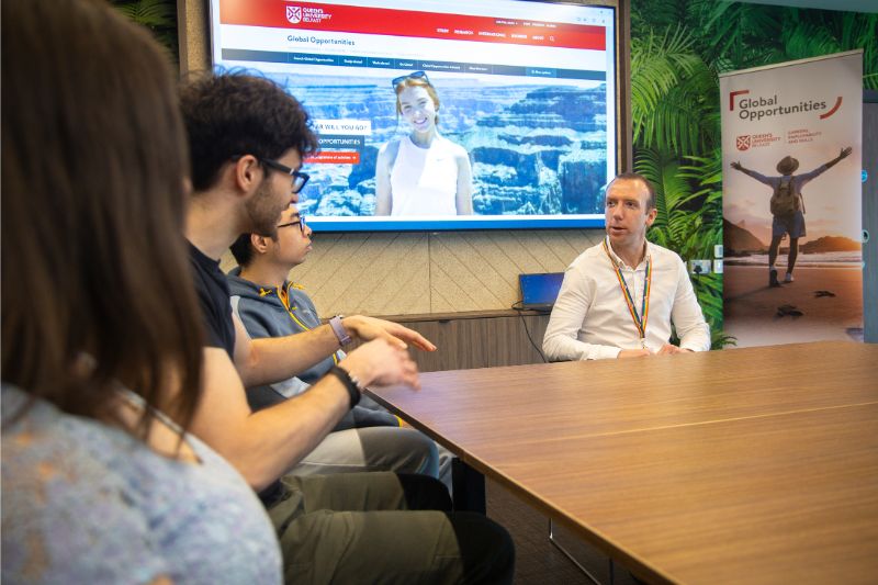 students sitting chatting to queen's staff member